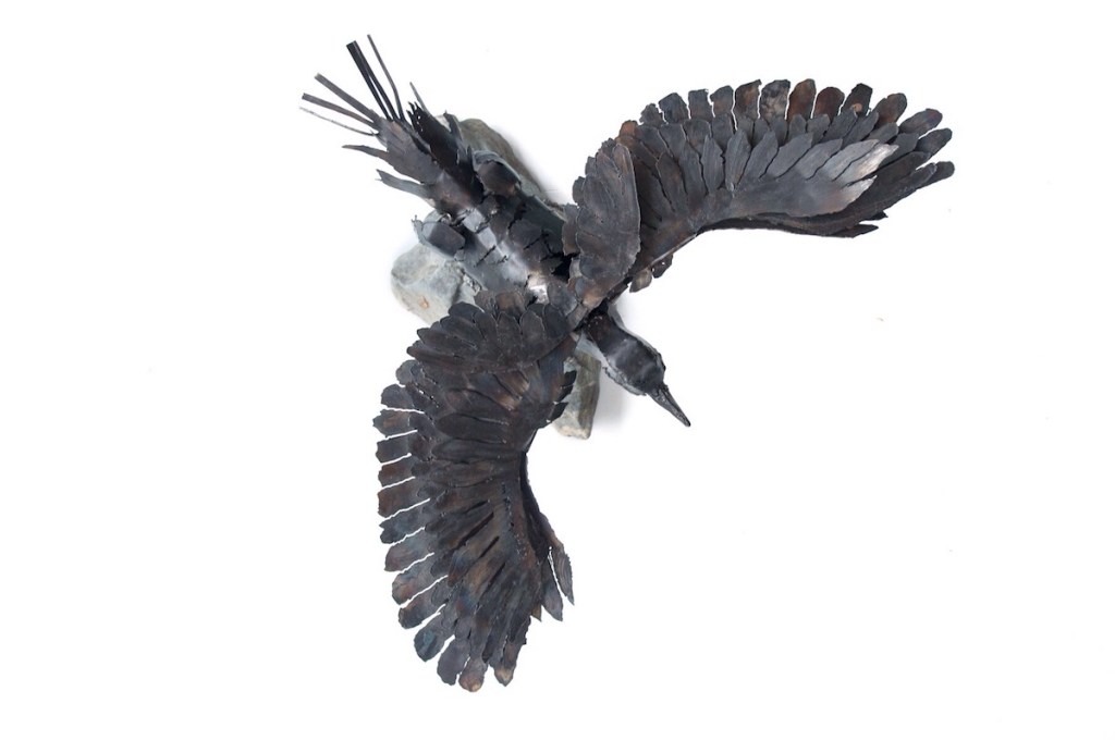 Overhead view. Sculpture of Arnold the eagle hearted crow - a crow who thinks he is an eagle, Arnold is protecting and defending intelligence and strength against a tide of ignorance.. Made from mild steel.  