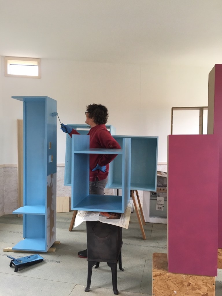 Margaret painting wearing clothes that match the furniture she is painting.