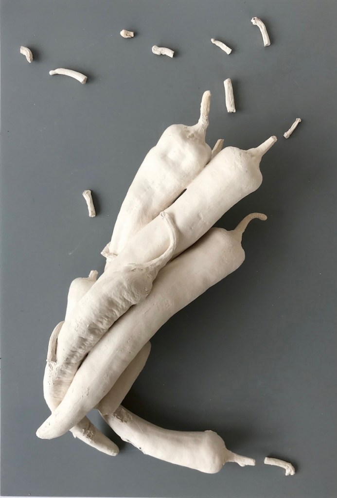 Explosively Hot Chillies - Group of white ceramic white chillies appears to spin on grey background board.