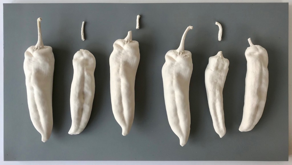 Fragmented Order - six large white ceramic Chilli peppers arrange in order across grey base board.