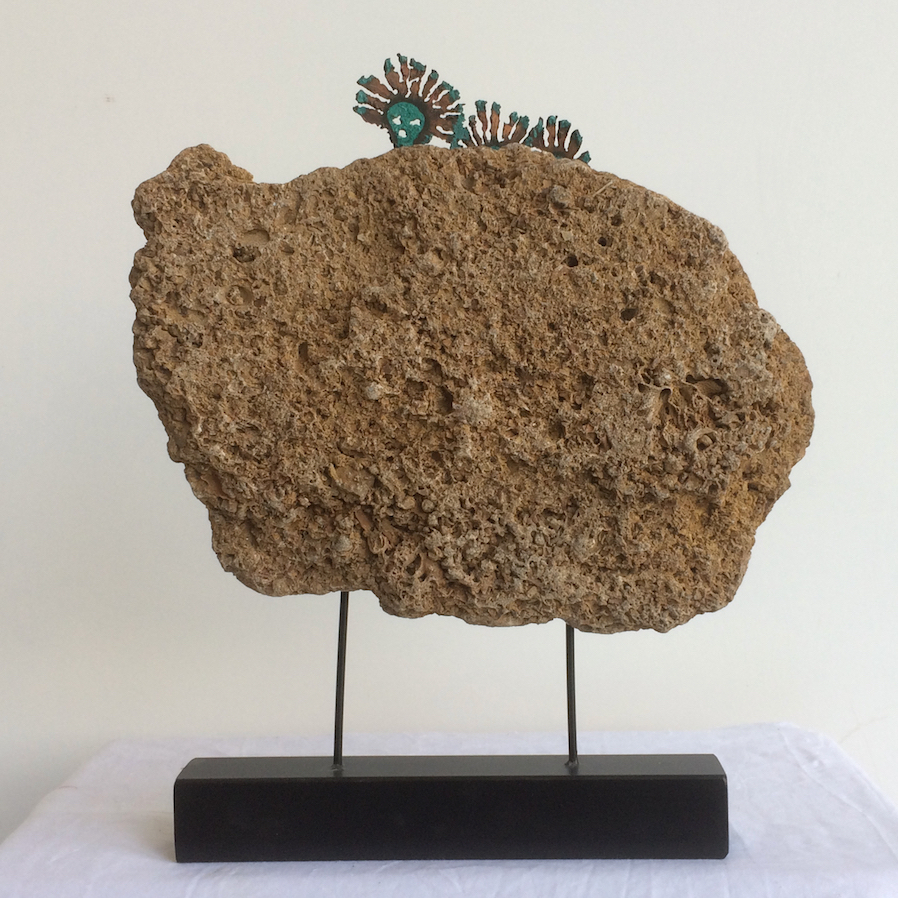 A piece of fossiliferous limestone, Coraline Crag is mounted on two rods. Three copper Spirit figures emerge from the rock and peek over to view what has gone before and is to come.